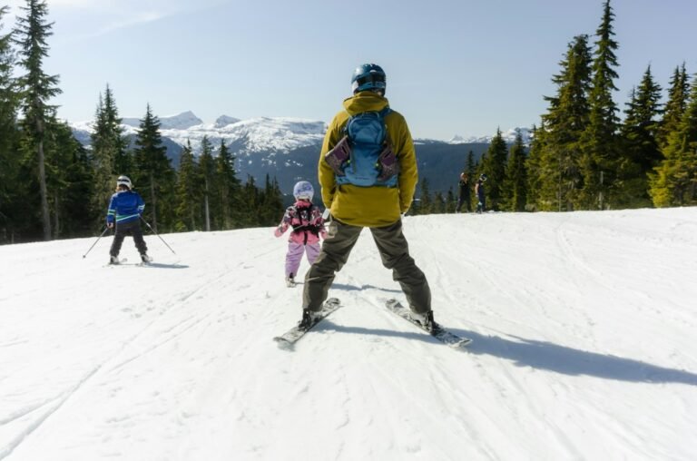 Adult skiing with two children on a snowy mountain slope